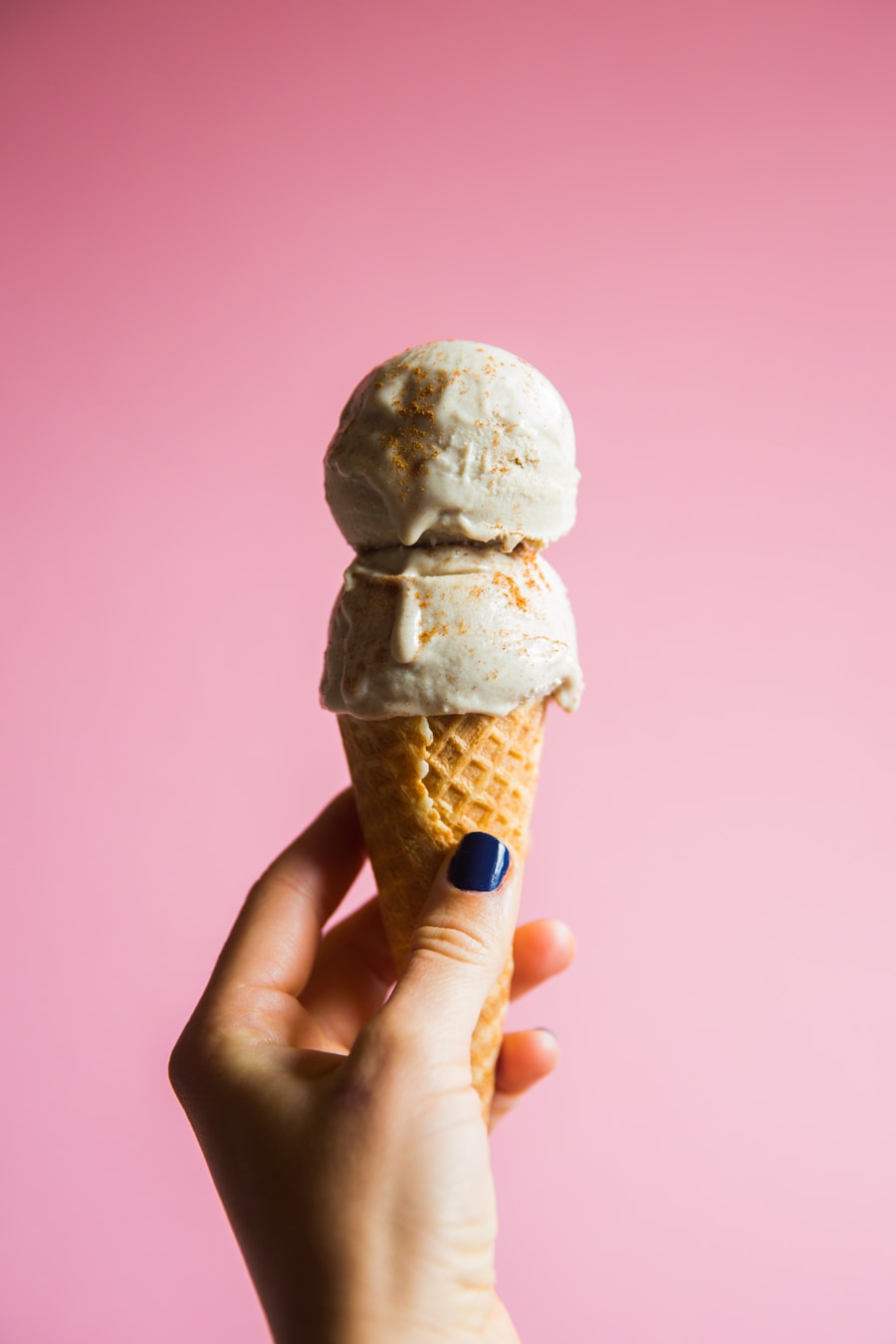 A hand holding a waffle cone with gelato