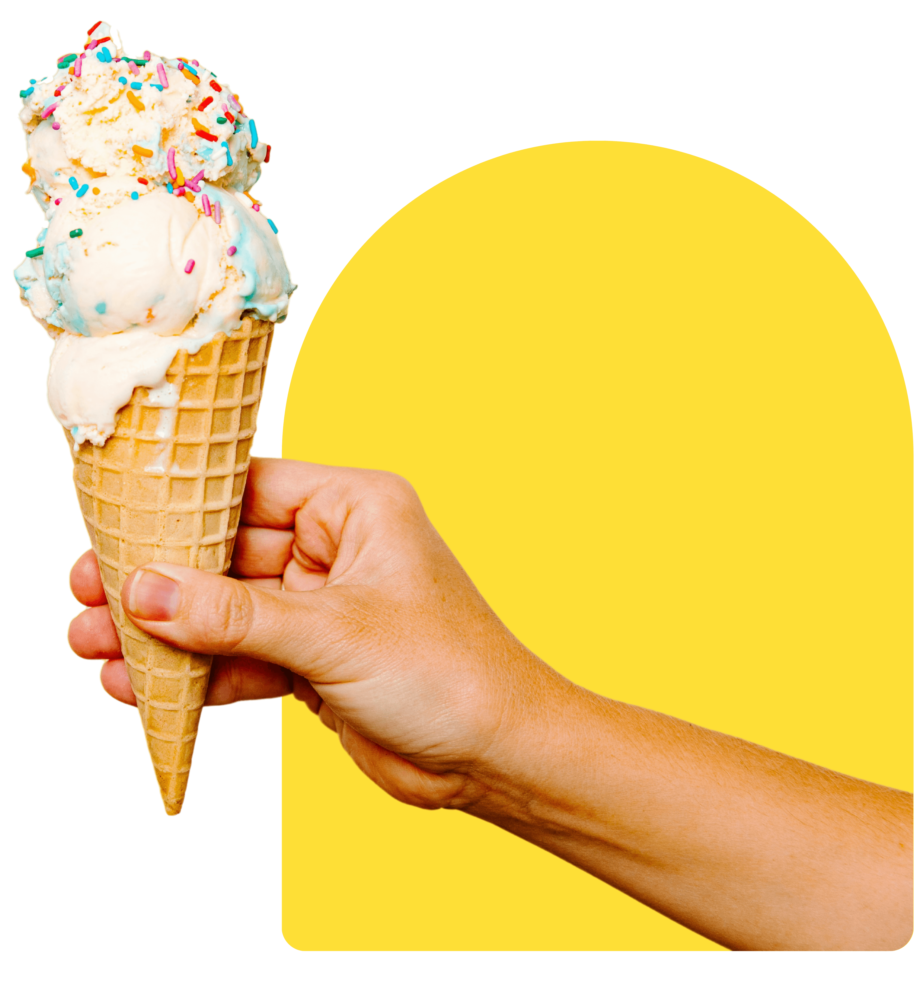 A hand holding a sprinkle-topped gelato cone in a waffle cone