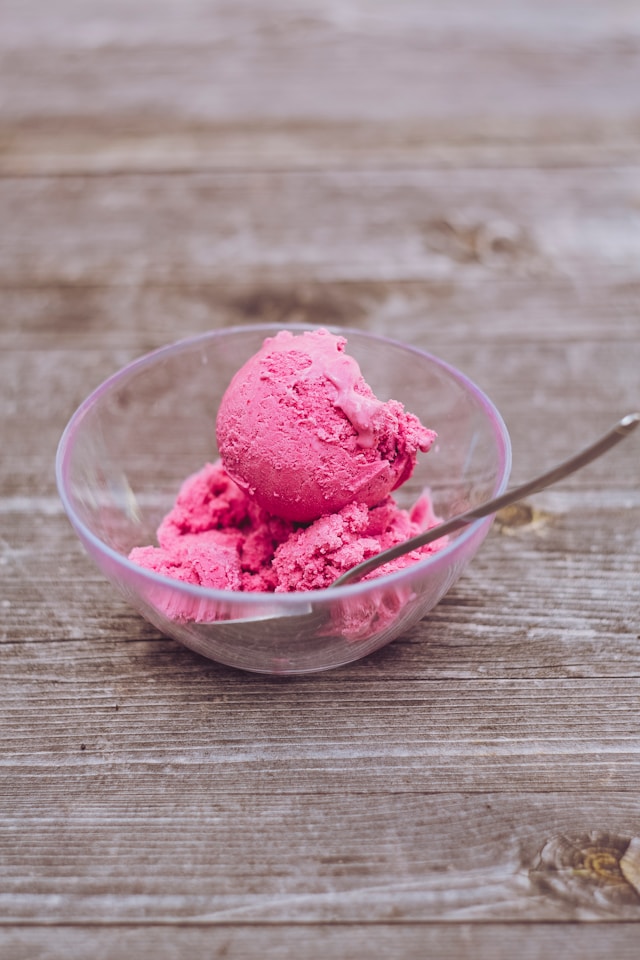 Strawberry gelato scooped into a clear glass bowl